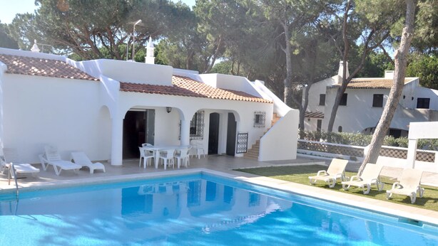 A swimming pool with white lounge chairs and a patio area. - Lovely and Cozy Golf Villa near Vilamoura Marina (Loulé)