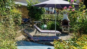A garden area with a lounge chair and umbrella, surrounded by plants and flowers. - Cheerful Apartment near Historic City Center of Haslach (Haslach im Kinzigtal)