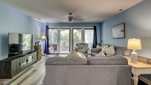 Ein Wohnzimmer mit einer Couch, einem Fernseher und einem Deckenventilator.