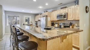A modern kitchen with wooden cabinets, a stainless steel refrigerator, a microwave, and a built-in oven. - Sunset Rentals | Tennismaster 801 | Dog Friendly (Hilton Head Island)