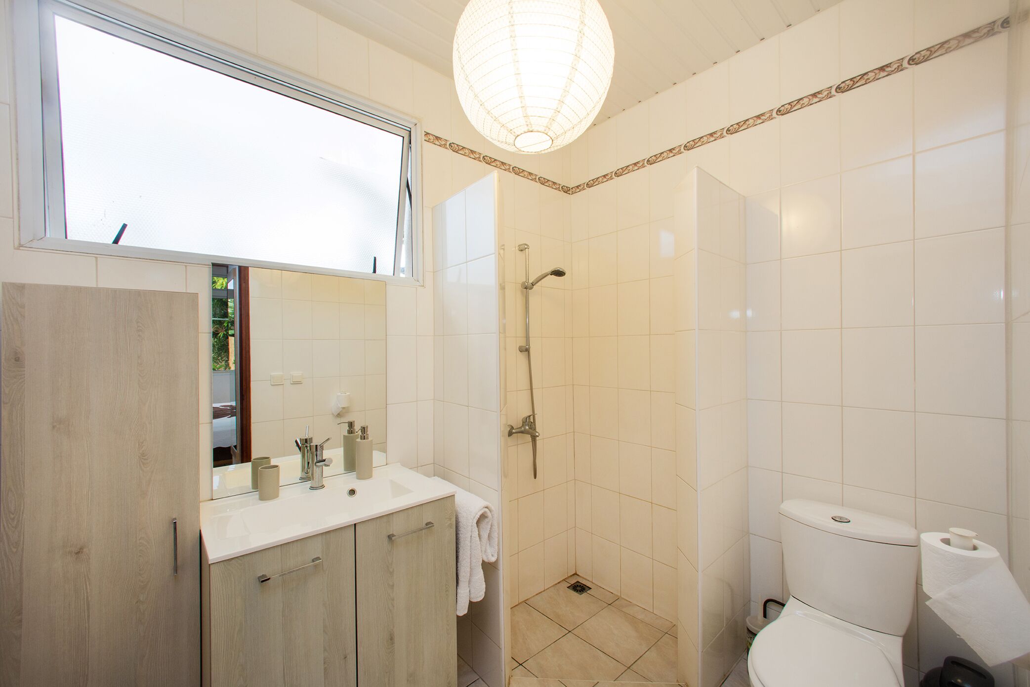 A bathroom with a wooden vanity, a shower, and a toilet.