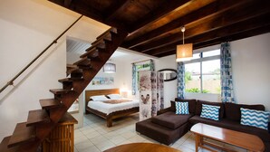 A modern interior with a wooden staircase, a bed, a sofa, and a dining table. - Villa TEPOE,  accès direct au lagon avec piscine et plage (Moorea-Maiao)