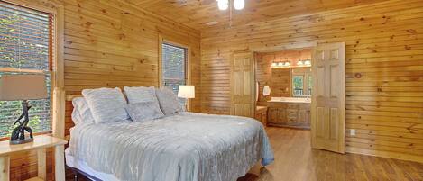 A wooden-paneled bedroom with a bed, bedside tables, and a ceiling fan.