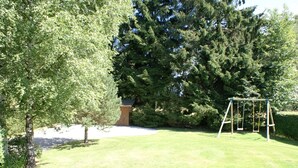 Une cour gazonnée avec une balançoire et un abri de jardin en bois.