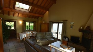 Un salon spacieux avec un plafond haut, un coin repas avec une table et des chaises, et une cheminée.
