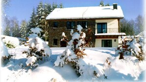 Un bâtiment en pierre de deux étages, avec un toit enneigé et un balcon.