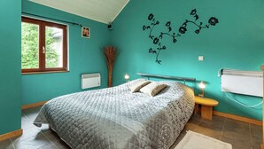 A bedroom with a bed, a window, a wall-mounted air conditioner, and a wall decoration. - Charming Cottage in Stoumont (Stoumont)
