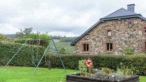 A stone house with a sloped roof, a swing set in the yard, and a no dog sign. - Charming Cottage in Stoumont (Stoumont)