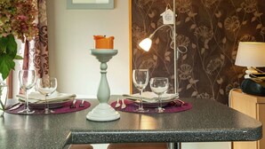 A dining area with a table set for two, featuring a candle centerpiece, wine glasses, and a floral-patterned wallpaper. - Charming Cottage in Stoumont (Stoumont)