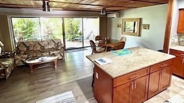 A spacious living area with a wooden ceiling, a sofa, a coffee table, and a kitchen island with cabinets.