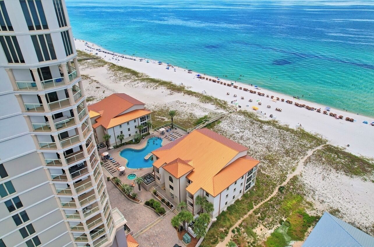 Een hoog hotel met een zwembad, toegang tot het strand en uitzicht op de oceaan.