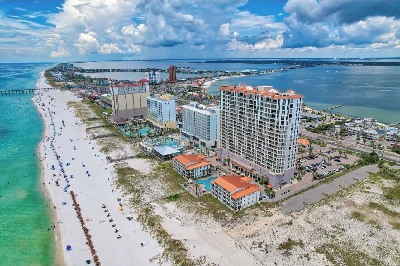 Ein Küstenhotel mit mehreren Gebäuden, einem Strand und einem Steg.