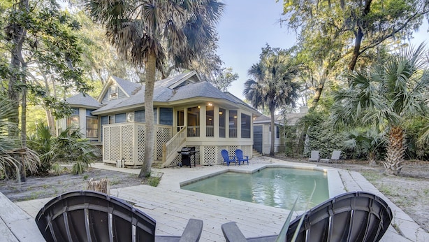 A house with a pool, two Adirondack chairs, and a covered patio area. - Sunset Rentals | Kingston Dunes 91 | Dog Friendly (Hilton Head Island)