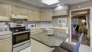 A kitchen with wooden cabinets, a granite countertop, a microwave, an oven, and a coffee maker. - Sunset Rentals | Kingston Dunes 91 | Dog Friendly (Hilton Head Island)