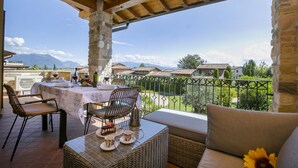 Eine Terrasse mit Esstisch, Korbmöbeln und Blick auf die umliegende Landschaft.
