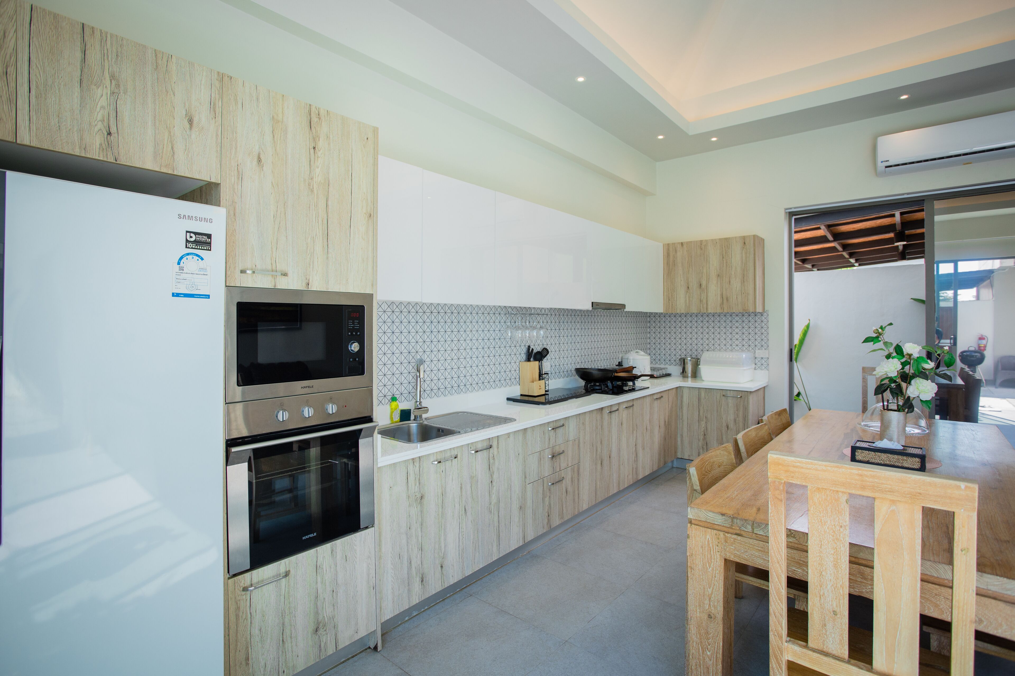 A modern kitchen with stainless steel appliances, wooden cabinets, and a dining area with a wooden table and chairs.