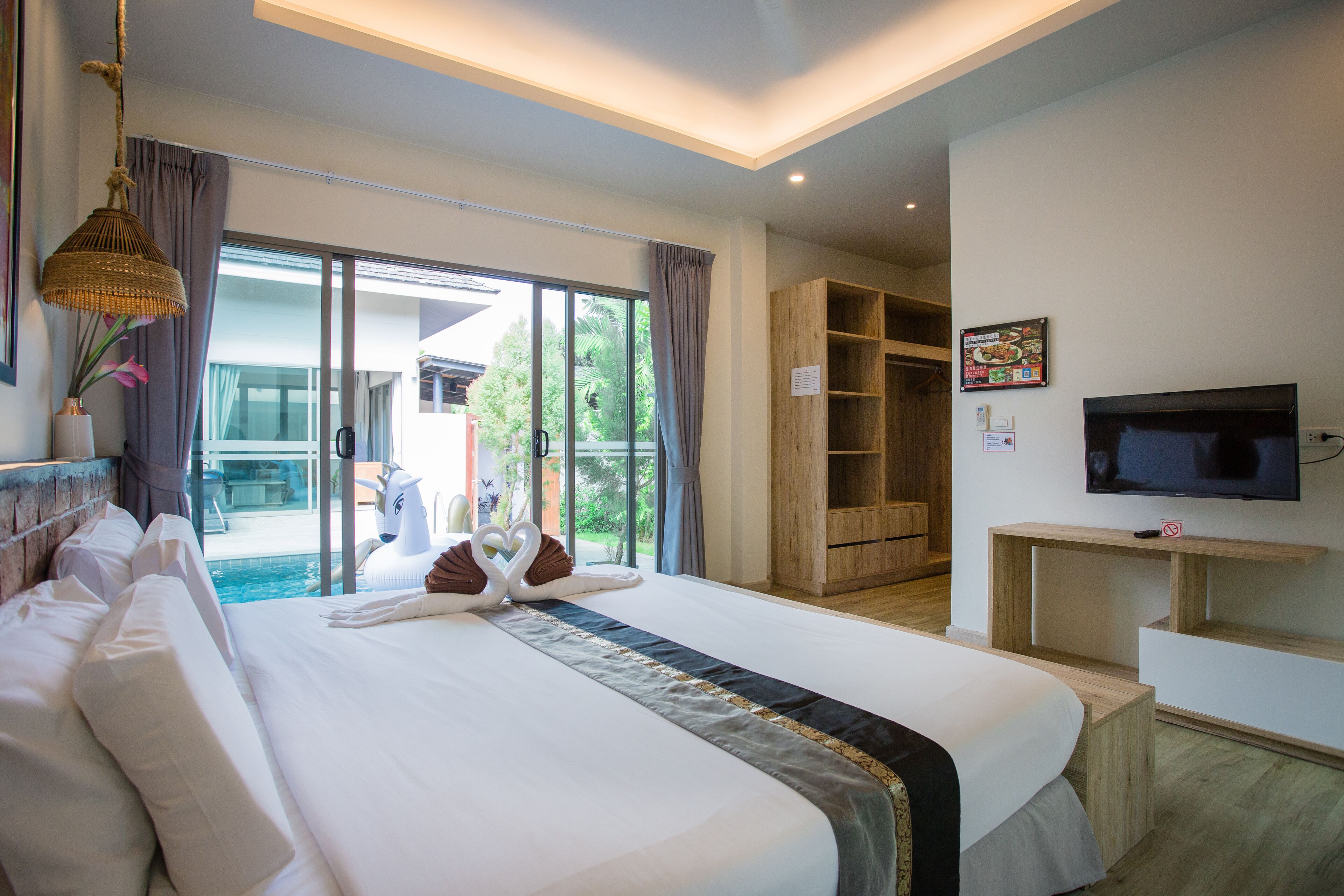 Una habitación de hotel con una cama grande, televisión, un mueble de madera y vistas al exterior.