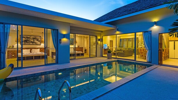 Et moderne hotel med swimmingpool, glasdøre der fører til et veloplyst interiør, og uhindret udsigt til poolområdet.