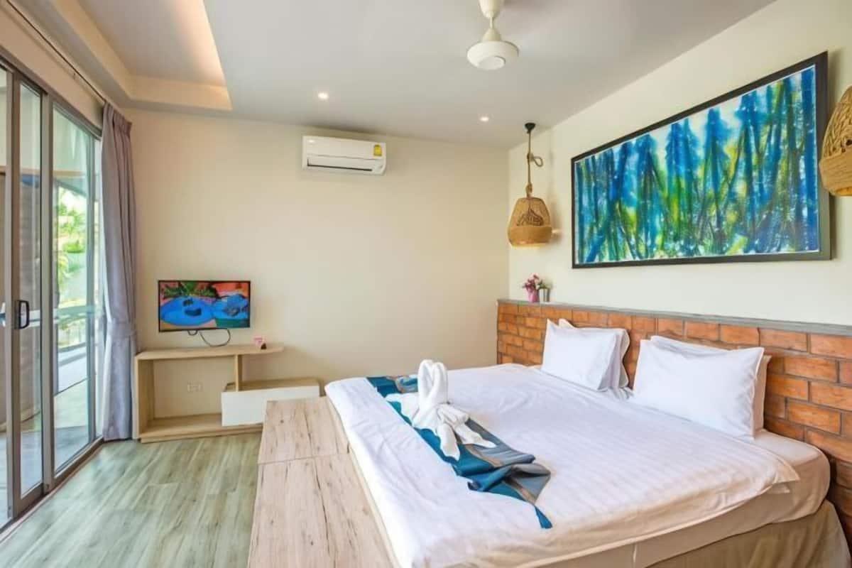 Ein Schlafzimmer mit einem großen Bett, einem Fernseher, einer Klimaanlage und einem Gemälde an der Wand.