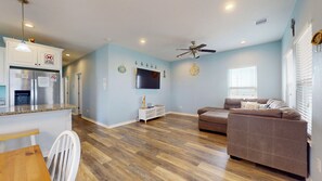 Un salon avec un canapé marron, un téléviseur et un ventilateur de plafond.