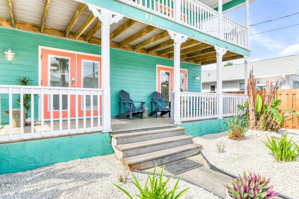 A two-story building with a porch, steps leading to the entrance, and outdoor seating.