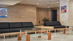 Um hall moderno com um sofá de couro preto, uma mesa de centro de vidro e piso de madeira.
