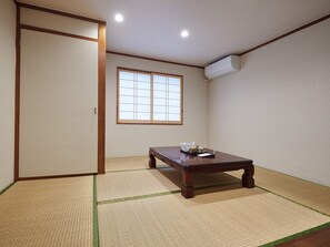 A traditional Japanese room with tatami flooring, a sliding door, a window, and a table with a tray of items. - Enagic Hotel Yamaichi (Naha)