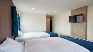 Quarto de hotel com duas camas, televisão de tela plana presa à parede e painel de madeira na parede.
