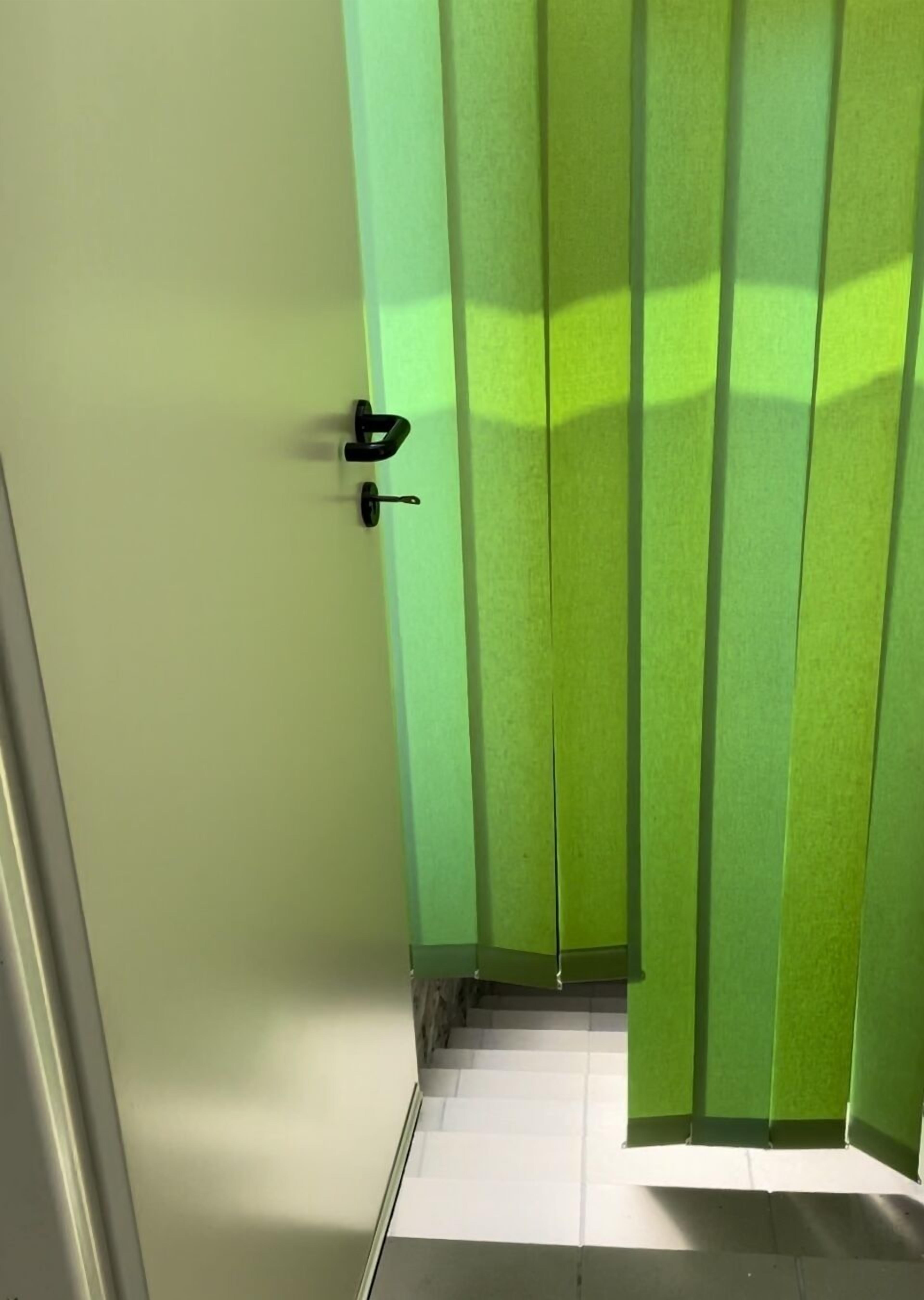 Un couloir avec une porte verte et un sol blanc.