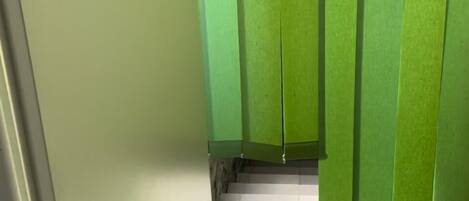 Un pasillo con una puerta verde y un suelo blanco.