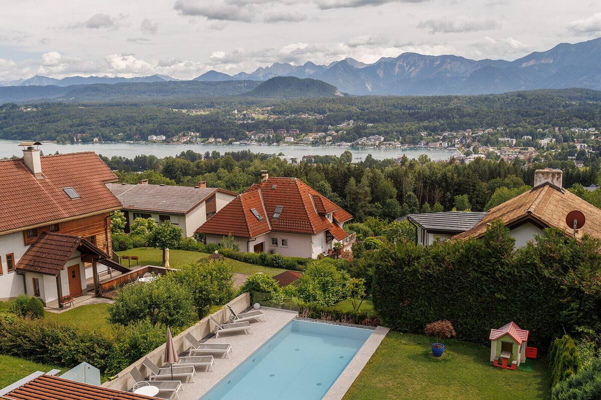 Un quartier résidentiel avec des maisons, une piscine et un lac, le tout surplombé par des montagnes.