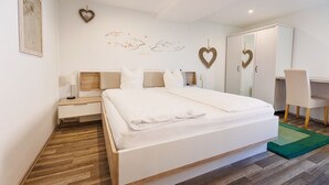 Een moderne slaapkamer met een groot bed, nachtkastjes, een bureau en een stoel.