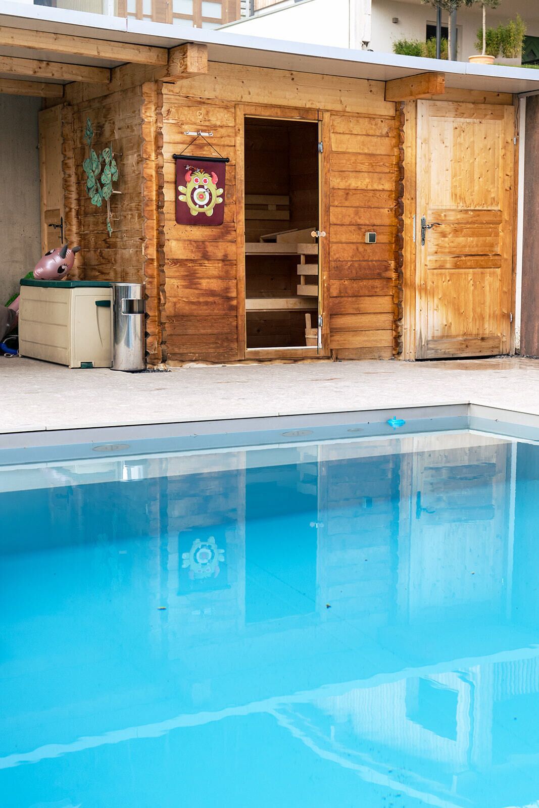 A wooden cabin with a pool, a small shed, and a pink toy.