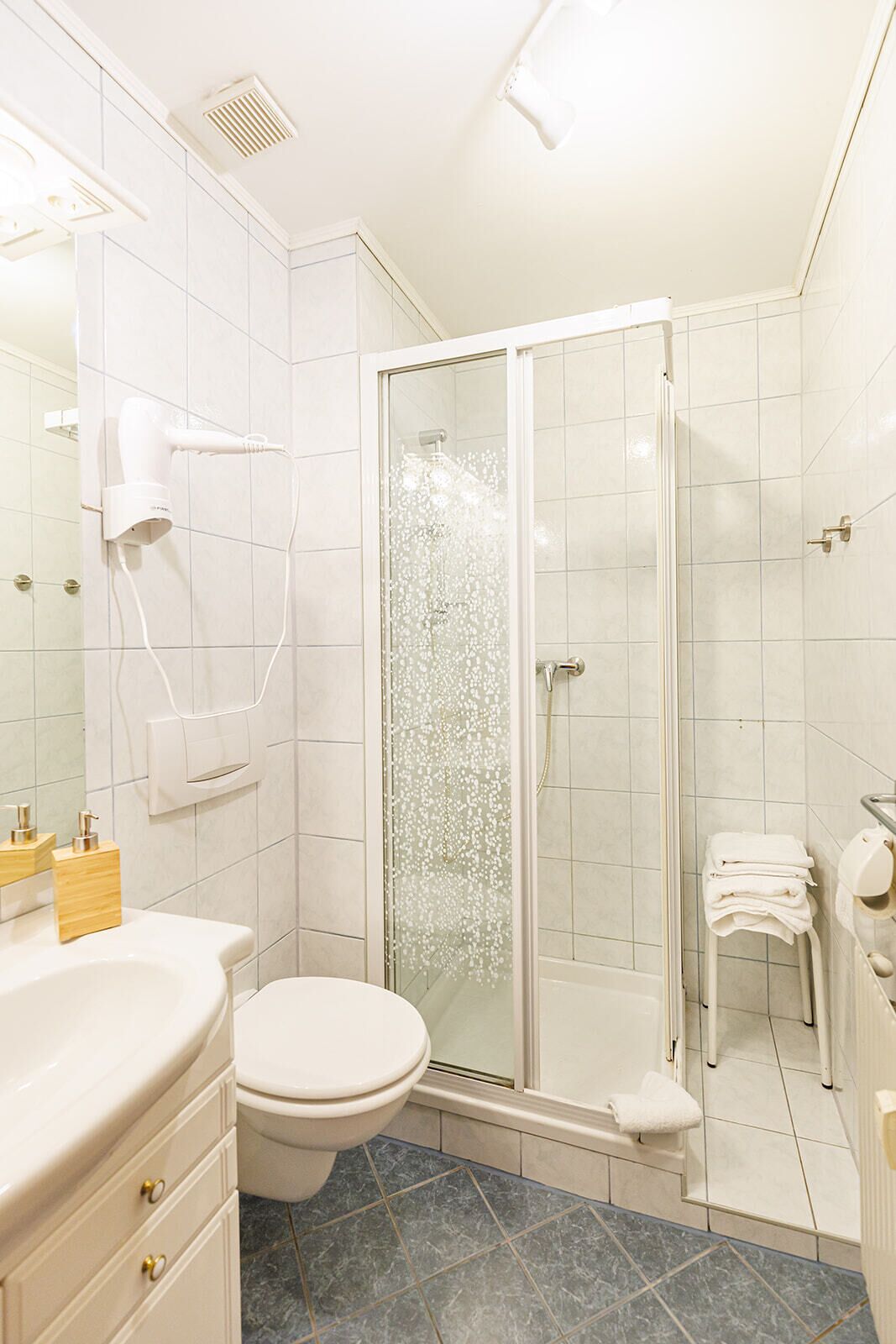 Une salle de bain moderne avec une douche à parois de verre, des toilettes blanches et un meuble-lavabo avec un miroir.