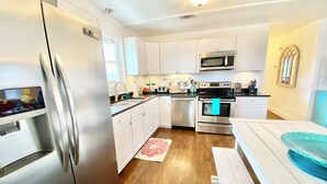 Una cocina moderna con electrodomésticos de acero inoxidable, armarios blancos y suelo de madera.