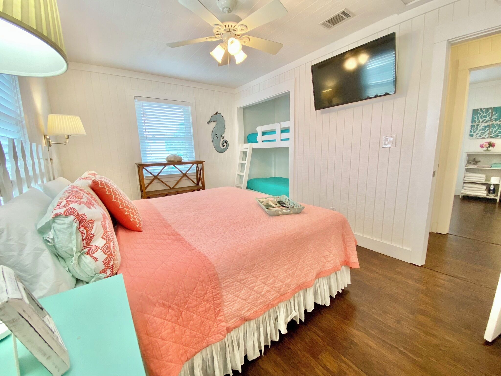 A bedroom with a bed, a ceiling fan, a TV, and a bunk bed.