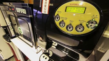 Una cafetera con pantalla digital, diversas opciones de café y un dispensador de agua caliente.
