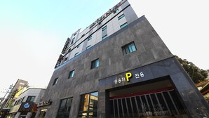 A modern building with a sign for a hotel and a parking garage. - Hotel Nuri (Osan)