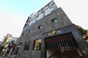 Un edificio moderno con un cartel de hotel y un estacionamiento.