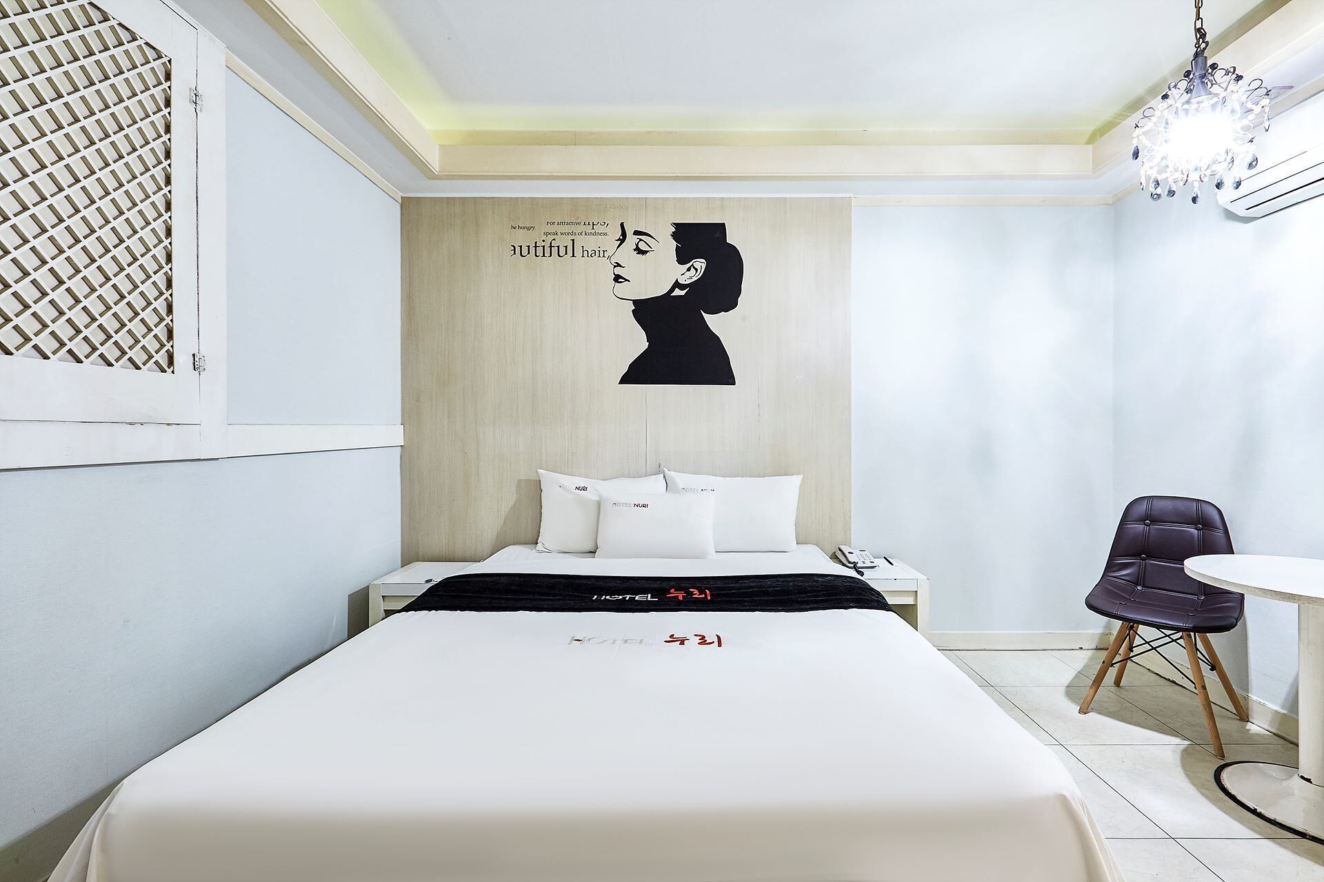 Een hotelkamer met een bed, een bureau, een stoel en een muur met een zwart silhouet en tekst.
