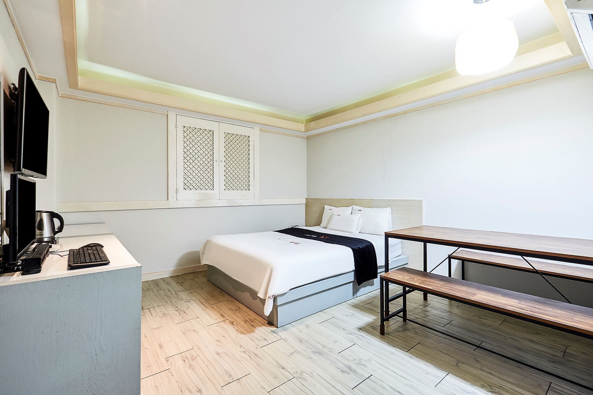 A hotel room with a bed, desk, and bench.