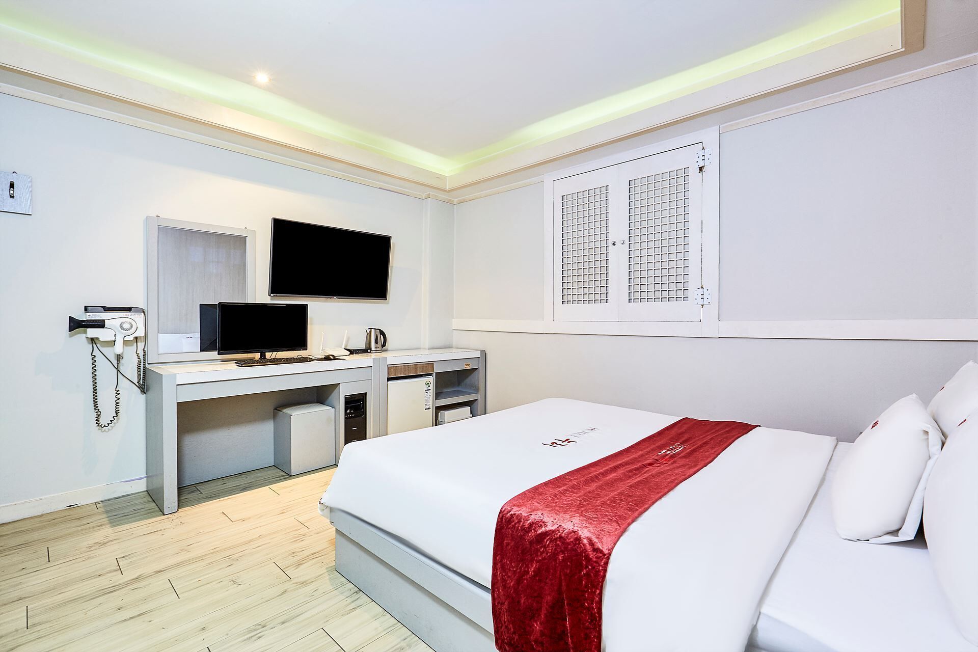 A hotel room with a bed, a desk with a computer, a telephone, and a television.