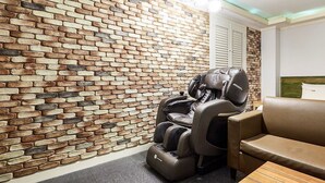 A massage chair in a room with a brick wall and a wooden table. - Hotel Nuri (Osan)