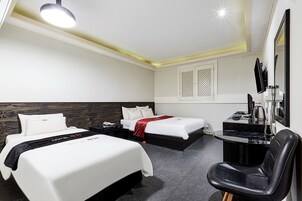 Habitación de hotel con dos camas, un escritorio con teléfono y un espejo.