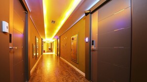 A hotel hallway with doors on both sides, a fire alarm, and a sign indicating room number 707. - Hotel Nuri (Osan)