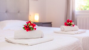A hotel room with two beds, each with a neatly folded white towel and a small bouquet of red flowers. - Modern Town Villa "Bona Mar" with Pool (cala ratjada)