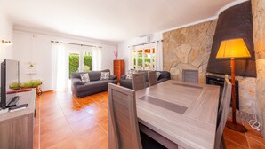 A modern living room with a sofa, a dining table, a TV, and a fireplace. - Modern Town Villa "Bona Mar" with Pool (cala ratjada)