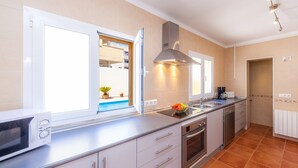 A modern kitchen with a microwave, oven, sink, and a window with a view of a balcony. - Modern Town Villa "Bona Mar" with Pool (cala ratjada)