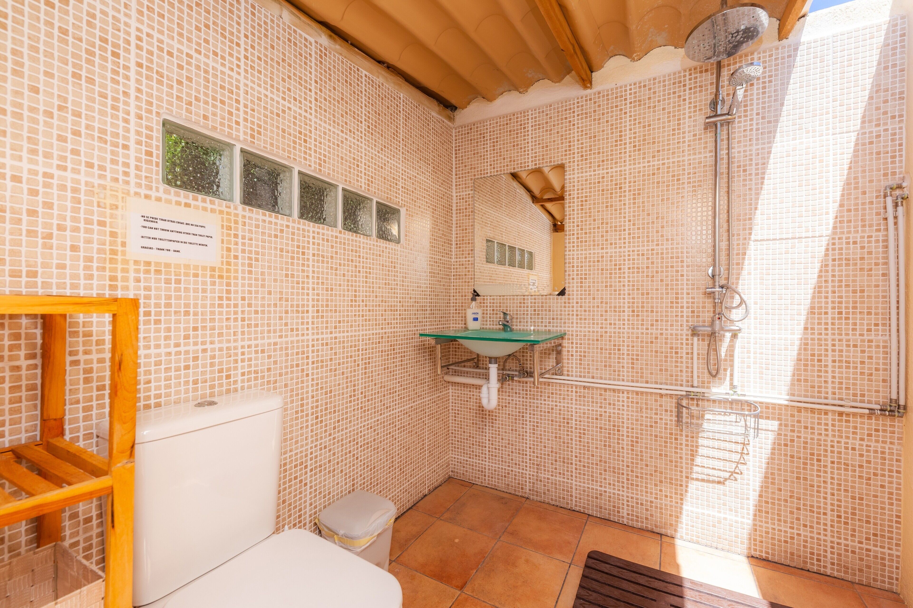 A bathroom with a toilet, sink, shower, and tiled walls.