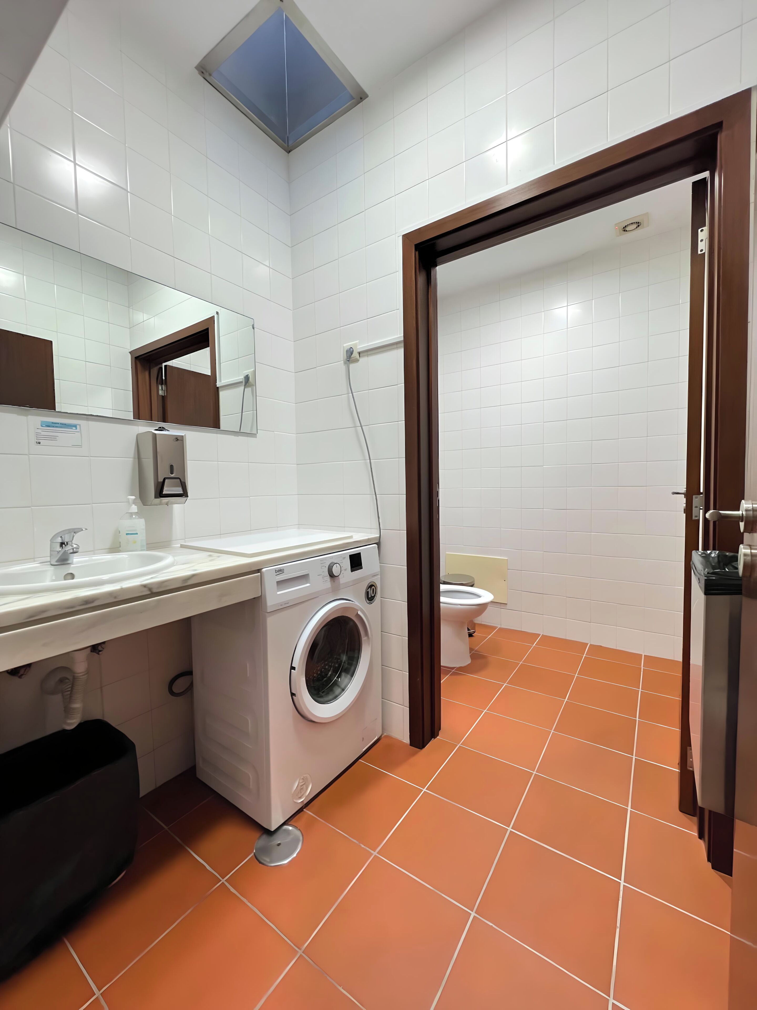 Un baño moderno con lavadora, lavamanos y retrete.